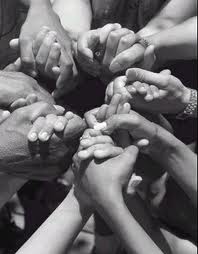 Several people holding hands together in prayer